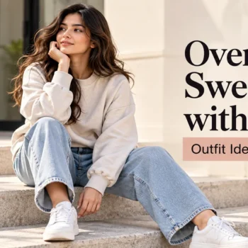 Woman wearing a cream oversized sweatshirt with light-wash jeans and white sneakers in a casual outdoor setting